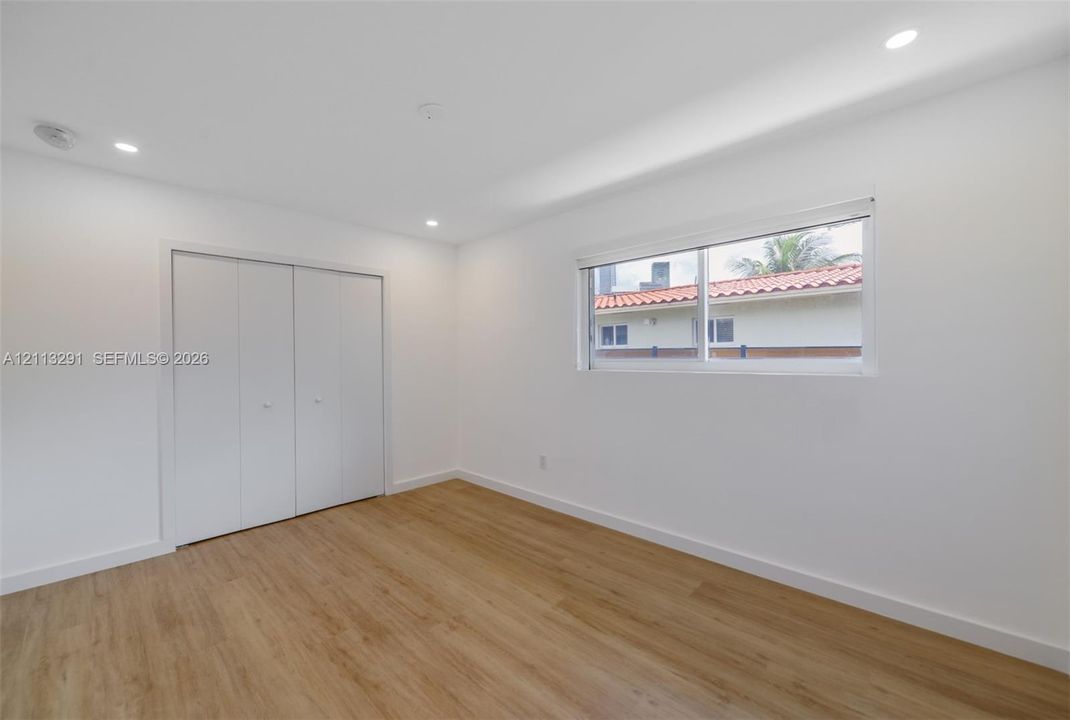 Neutral interior featuring wood-finish flooring, recessed lighting, and a double-door closet