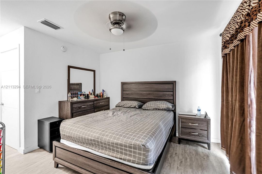 Neutral-toned wall finish, wood-finish flooring, and a ceiling-mounted fan with integrated lighting