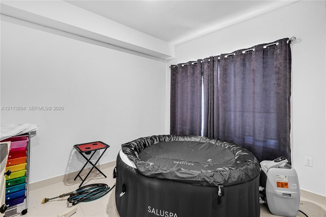 Interior space featuring tile flooring, neutral walls, and a window with hardware-mounted curtain rods