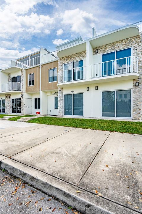 Multi-level exterior featuring stacked stone accents, smooth-finish siding, private balconies with white railings, and sliding glass doors