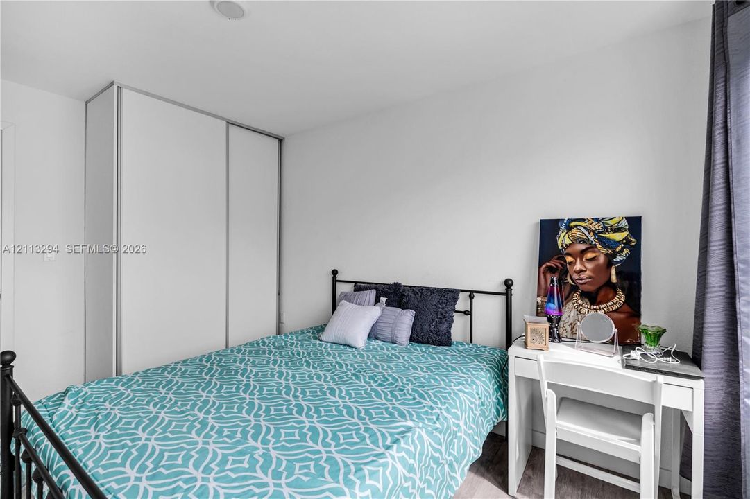 Room featuring neutral wall paint, wood-finish flooring, and a floor-to-ceiling built-in wardrobe with sliding doors