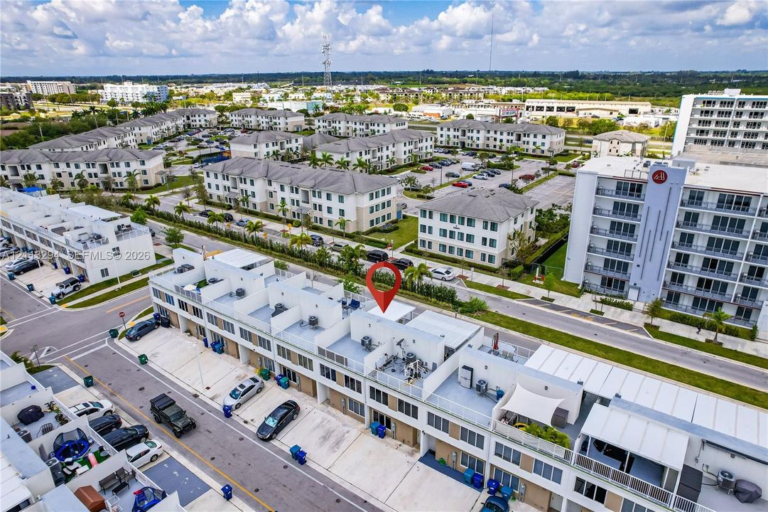 Aerial perspective of a multi-level residential structure featuring white exterior facades, flat rooflines, and rooftop terraces with metal railing enclosures
