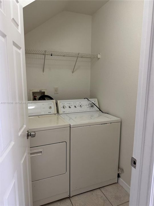 Dedicated laundry area featuring tile flooring and integrated wire shelving