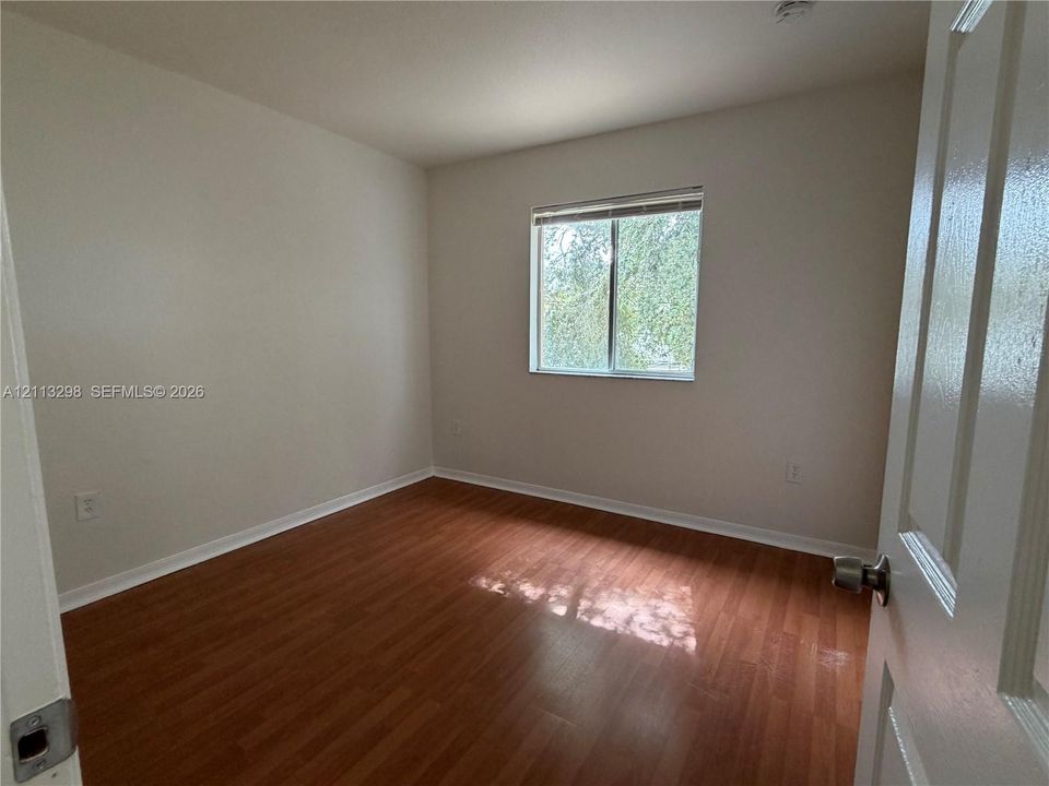 Neutral-toned interior space featuring wood-finish flooring and a single-pane window