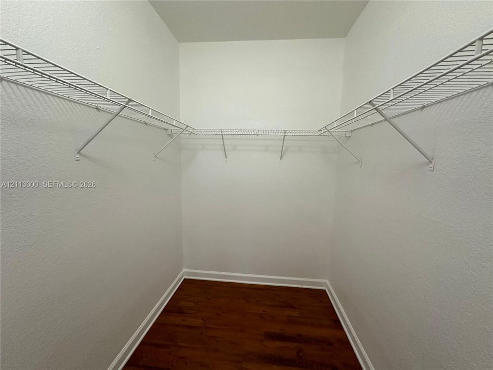 Walk-in storage space featuring wood-finish flooring and installed white wire shelving