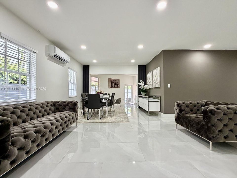 Large-format polished tile flooring, wall-mounted ductless climate control unit, recessed lighting, and accent wall featuring a neutral color palette