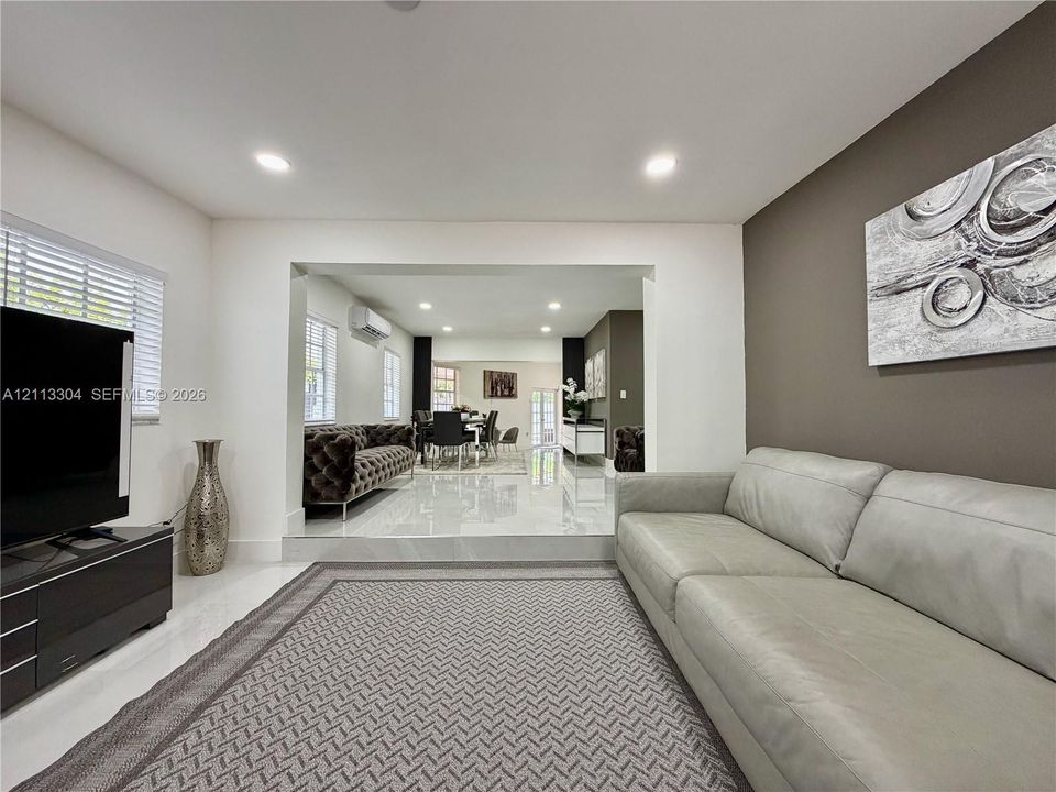 Sunken living area featuring large-format tile flooring, recessed lighting, and a prominent accent wall