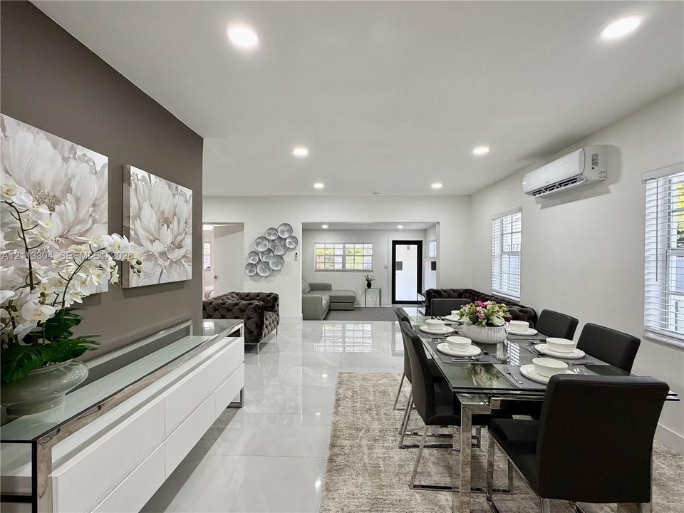 Open-concept space featuring polished tile flooring, recessed lighting, wall-mounted climate control unit, and crisp neutral wall tones