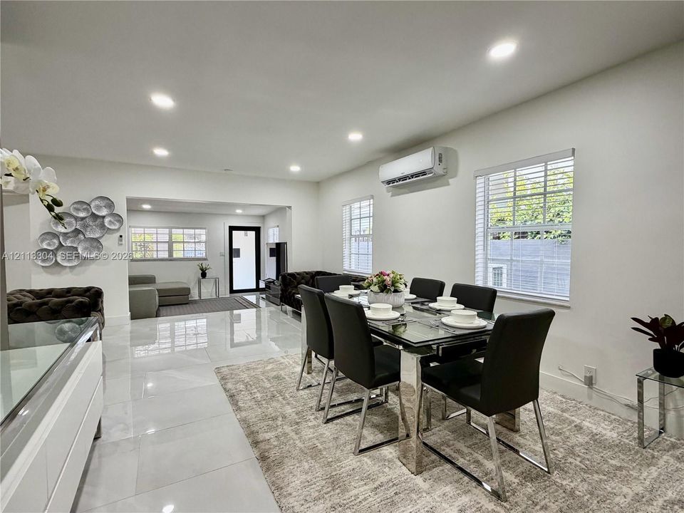 Polished tile flooring, recessed lighting, wall-mounted climate control unit, and multiple windows with white horizontal blinds