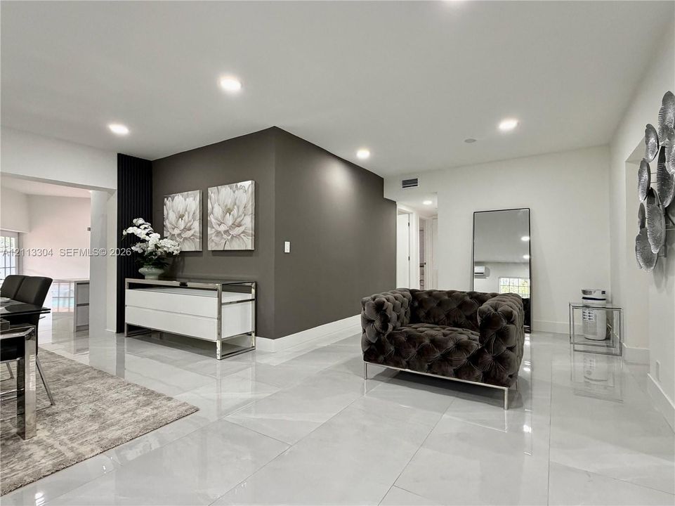 Large-format tile flooring, recessed ceiling lighting, and a dark accent wall featuring vertical slat detailing