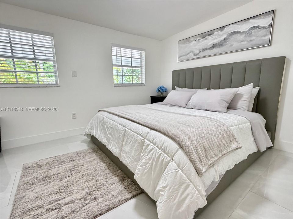 Neutral-toned interior featuring large-format tile flooring and two windows with adjustable horizontal blinds