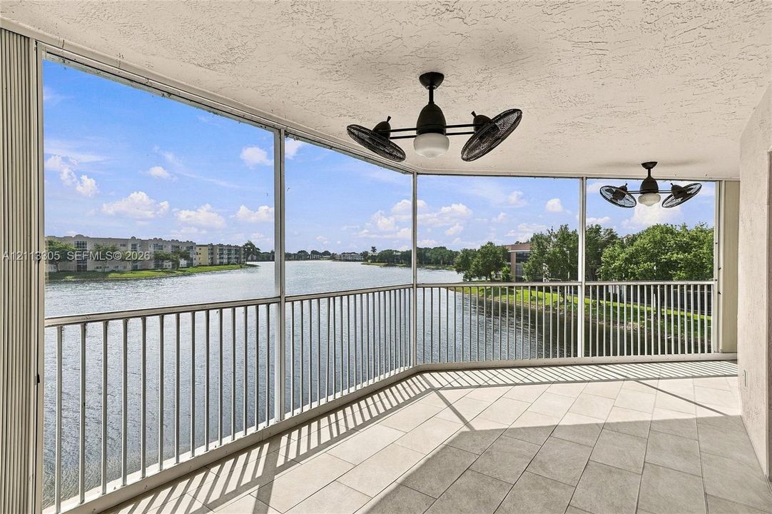 Screened-in balcony featuring tile flooring, metal railings, and dual multi-blade ceiling fans with integrated lighting