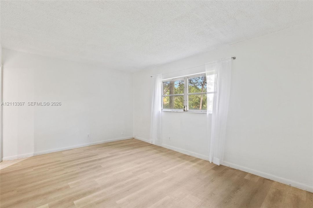 Interior room featuring wood-finish flooring, white walls, and a multi-pane window