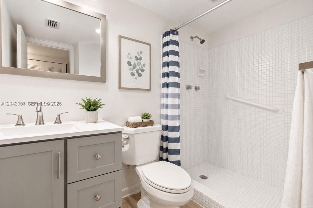 Bathroom featuring a vanity with grey cabinetry, white countertop, rectangular sink, and polished metal faucet