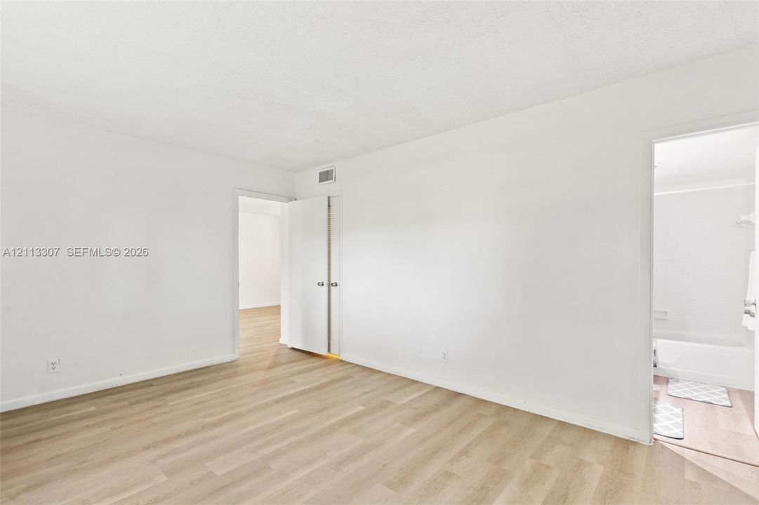 Neutral interior featuring wood-finish flooring, white walls, and a closet with double doors