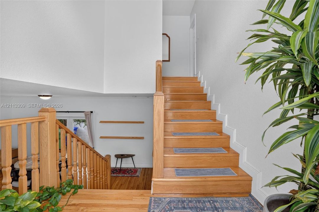 Staircase featuring natural wood handrails, wood-finish treads, and built-in shelving