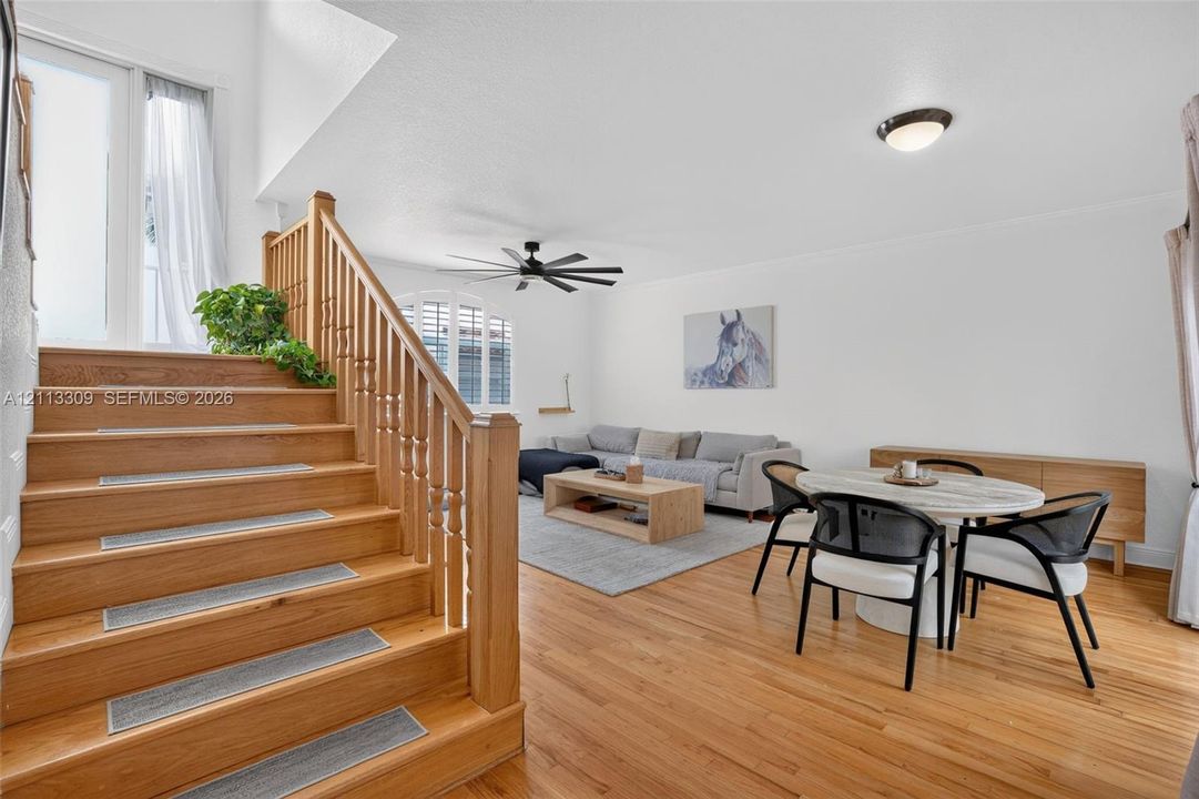 Wood-finish flooring, staircase with a wood balustrade and handrail, vaulted ceiling, and an arched window
