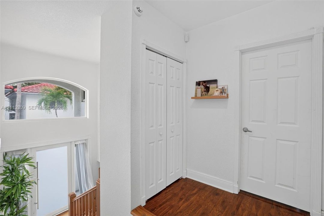 Wood-finish flooring, white paneled interior doors, bi-fold closet doors, and a semi-circular fixed window