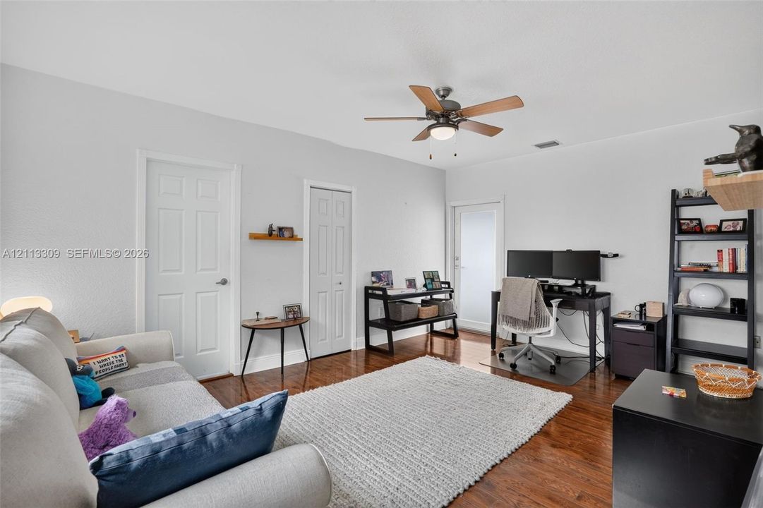 Room featuring wood-finish flooring, a ceiling fan with integrated lighting, and a glass-panel exterior door