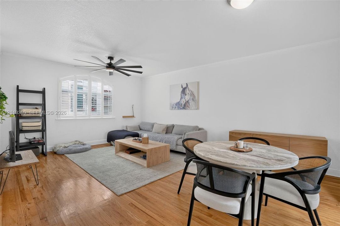 Wood-finish flooring, multi-pane arched window, and a multi-blade ceiling fan