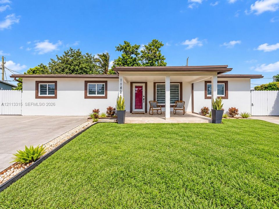 Single-story exterior featuring a covered front porch with structural columns, multi-pane windows with dark trim, and a concrete driveway