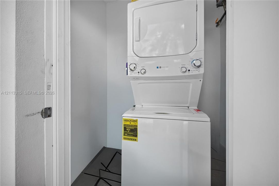 Built-in stacked laundry unit with white finish and neutral wall enclosure