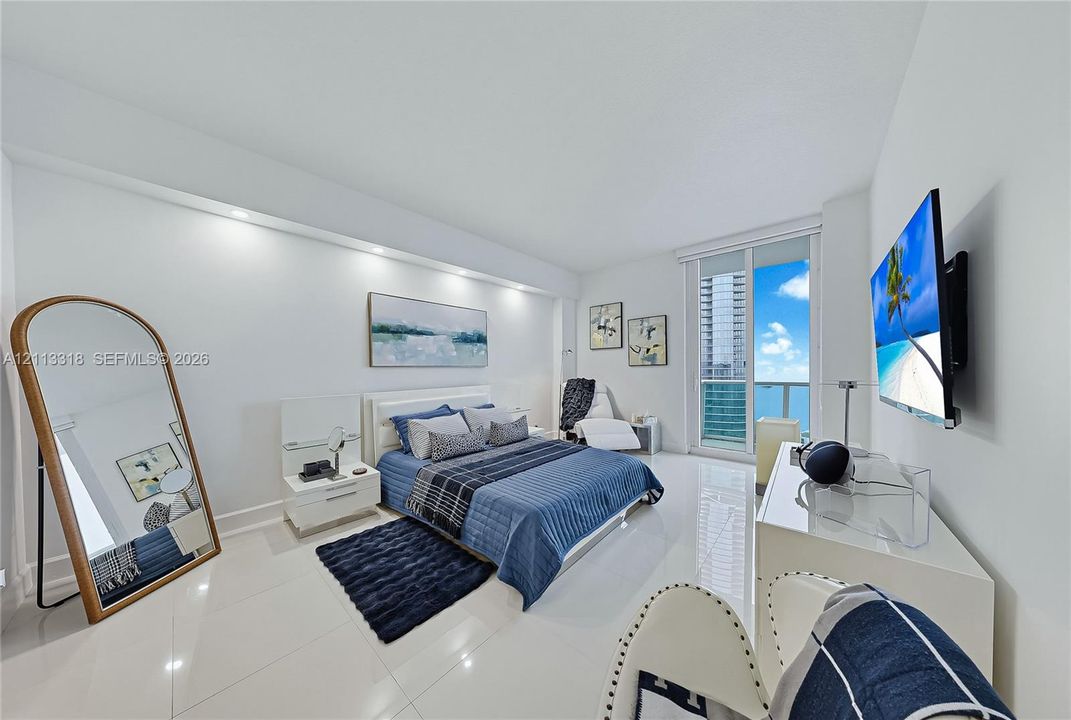 Interior space featuring large-format tile flooring, recessed architectural lighting, and floor-to-ceiling glass paneling with balcony access
