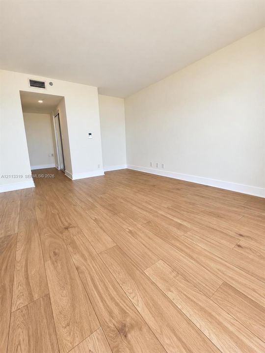 Neutral-toned interior space featuring light wood-finish flooring and recessed ceiling lighting