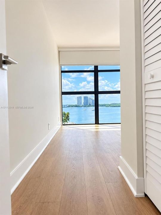 Floor-to-ceiling windows with black framing, wood-finish flooring, and integrated louvered closet doors