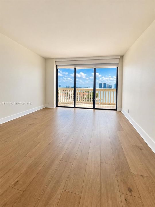 Interior space featuring wood-finish flooring, floor-to-ceiling sliding glass doors, and a private balcony with balustrade railings