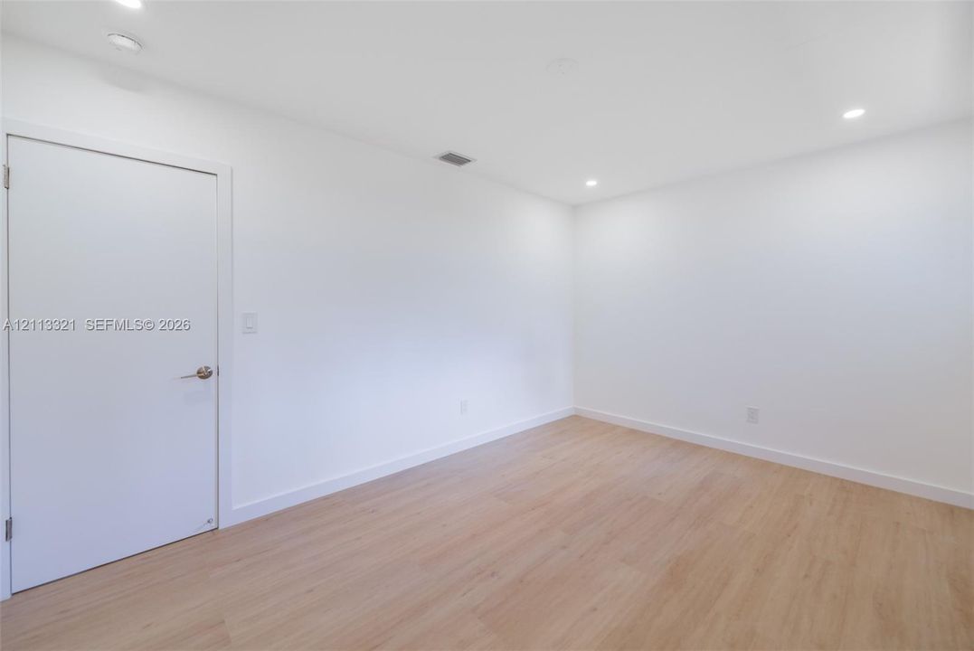 Neutral interior space featuring wood-finish flooring, crisp white walls, and recessed ceiling lighting