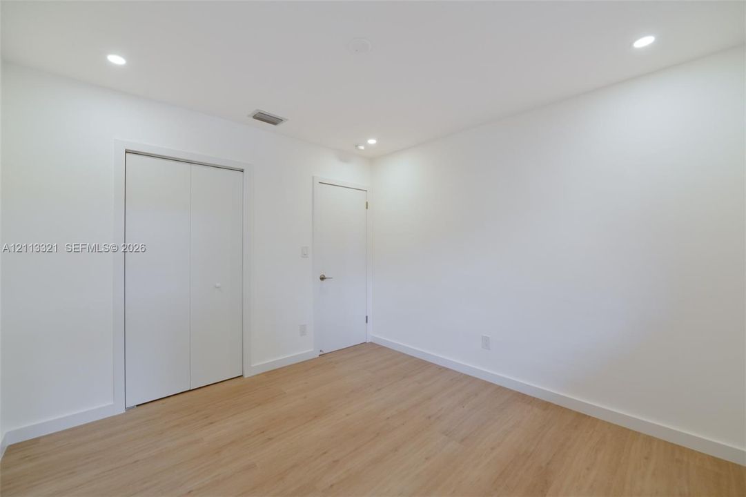 Neutral interior featuring wood-finish flooring, recessed lighting, and white cabinetry doors