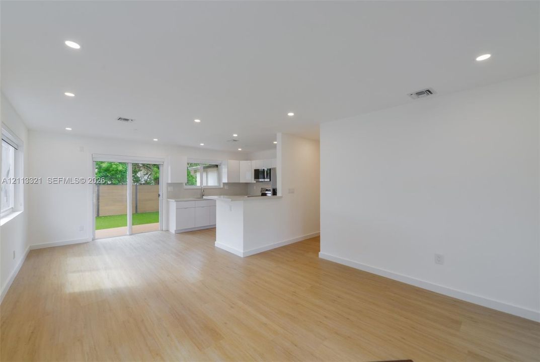 Open interior featuring wood-finish flooring, recessed lighting, white cabinetry, a peninsula counter, and sliding glass doors