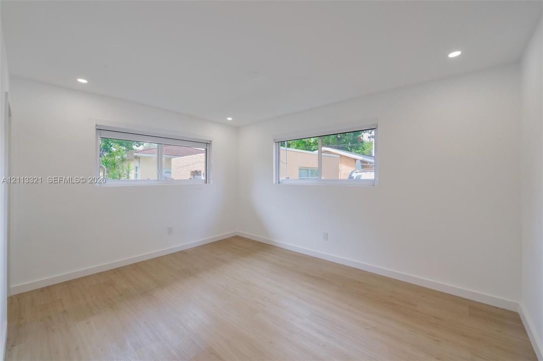 Bright interior room featuring wood-finish flooring, recessed lighting, and dual slider windows