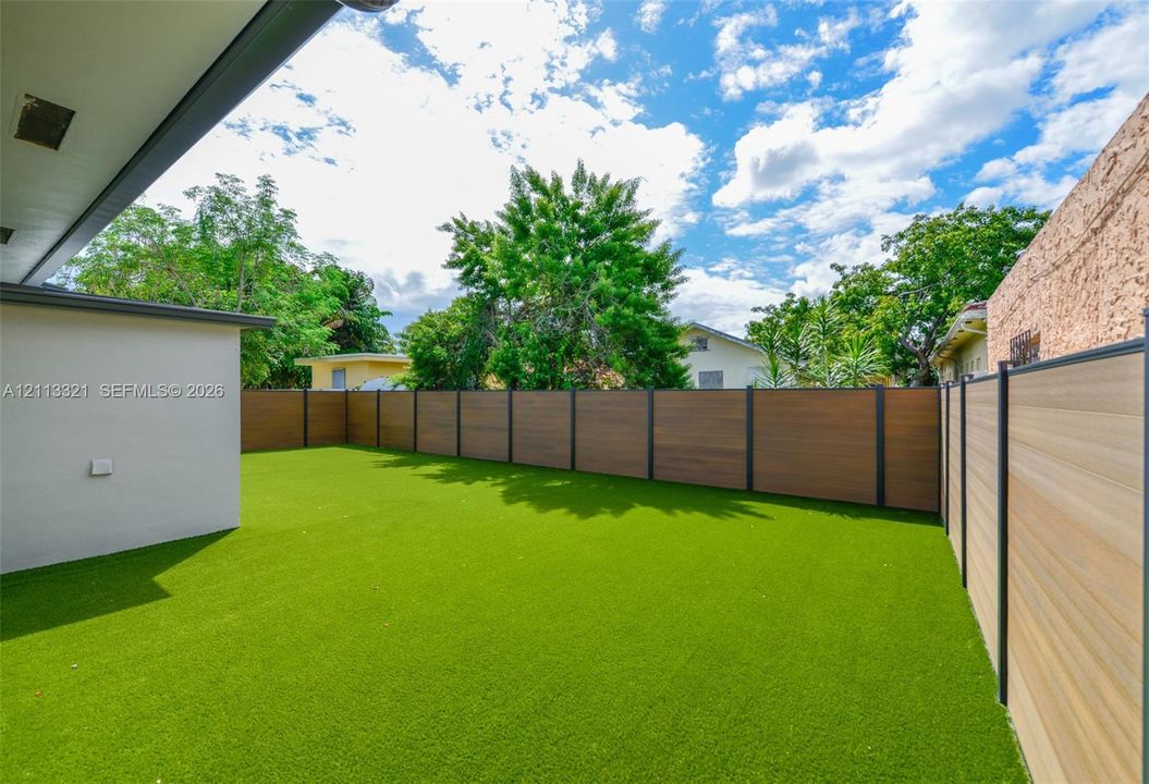 Private backyard featuring synthetic turf and horizontal privacy fencing with metal posts