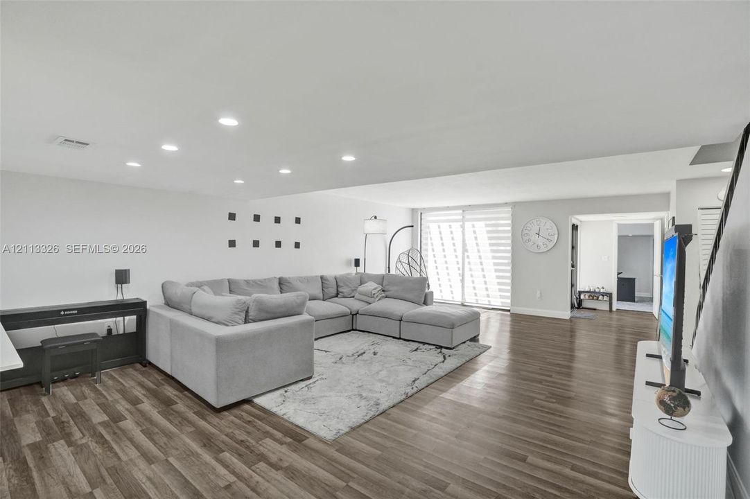 Open-concept interior featuring wood-finish flooring, recessed lighting, and glass sliding doors