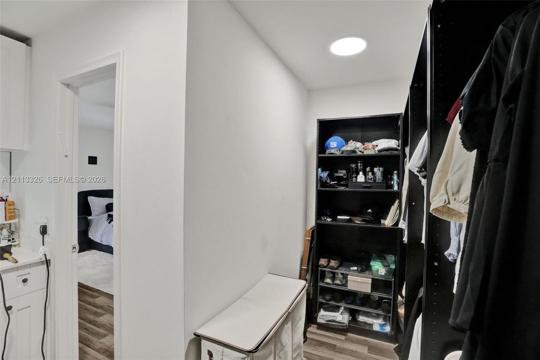 Walk-in closet featuring wood-finish flooring, recessed ceiling lighting, and built-in shelving units
