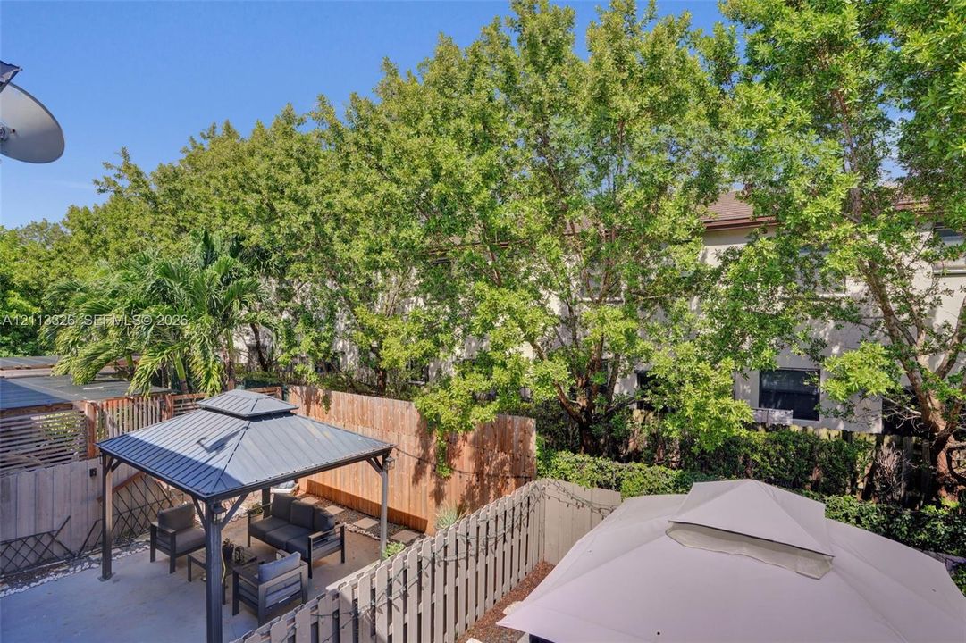 Outdoor space featuring a concrete patio, wood-style privacy fencing, and a permanent metal-roof gazebo