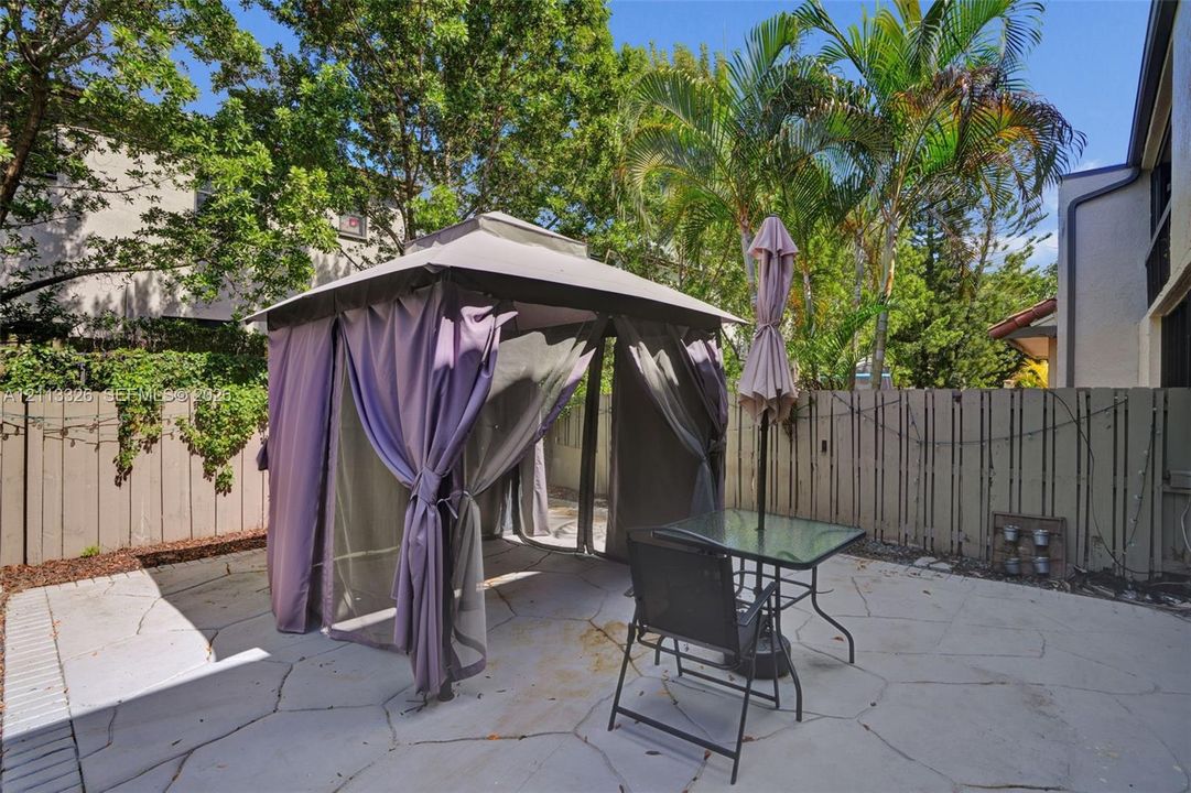Flagstone-style paved patio enclosed by vertical wood fencing, featuring mature palm trees and established perimeter landscaping