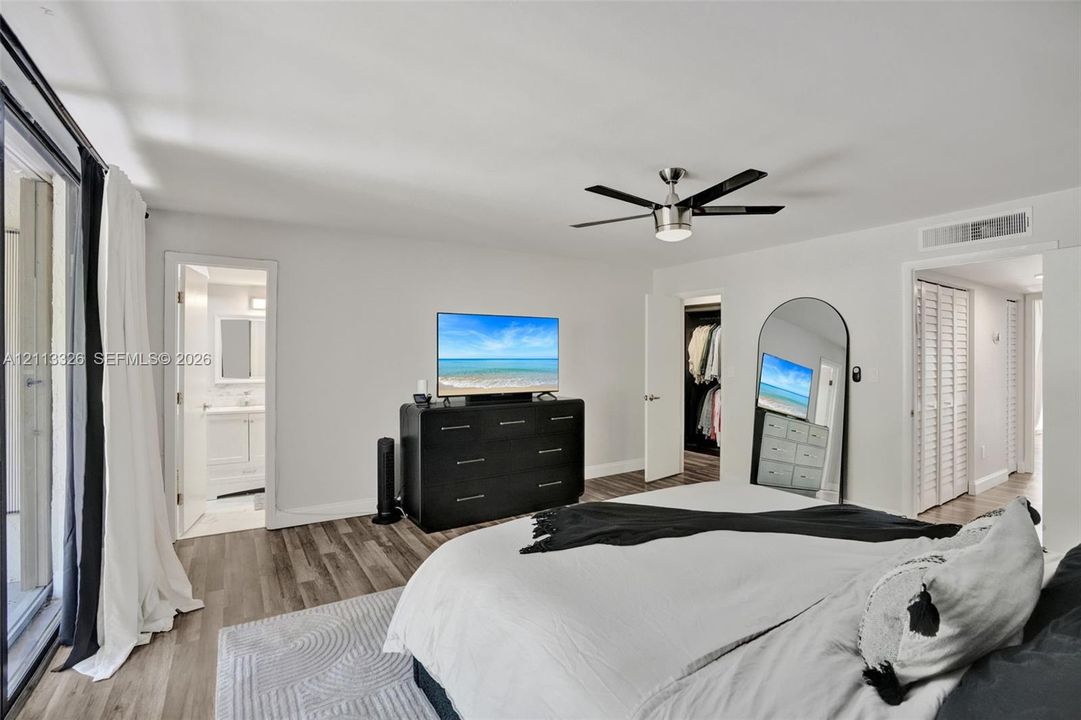 Wood-finish flooring, ceiling fan with integrated lighting, and louvered closet doors
