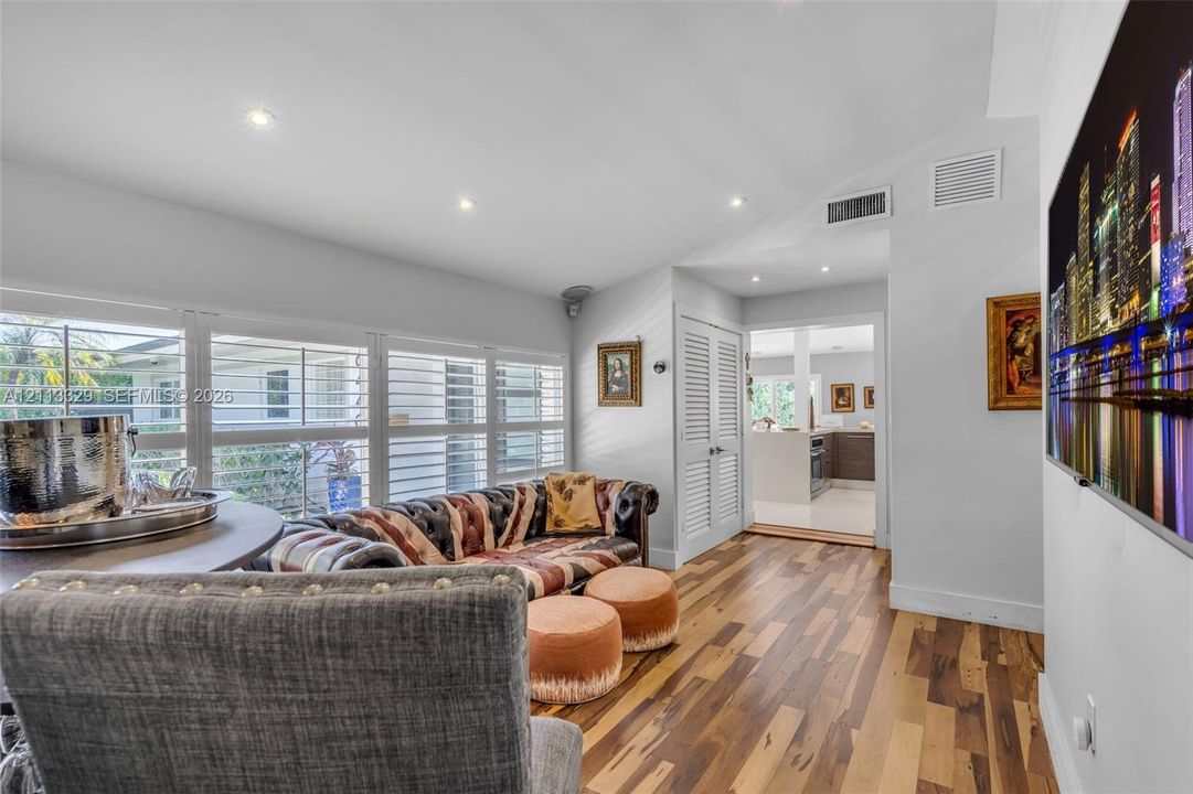 Wood-finish flooring, vaulted ceilings with recessed lighting, and large windows with integrated plantation shutters