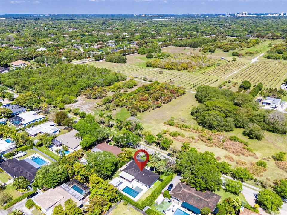Aerial perspective of a property featuring a private swimming pool, expansive grounds, mature landscaping, and a multi-pitched roofline