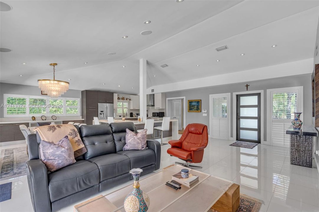 Vaulted ceilings with recessed lighting, tile flooring, tiered crystal chandelier, and exterior door with frosted glass panels