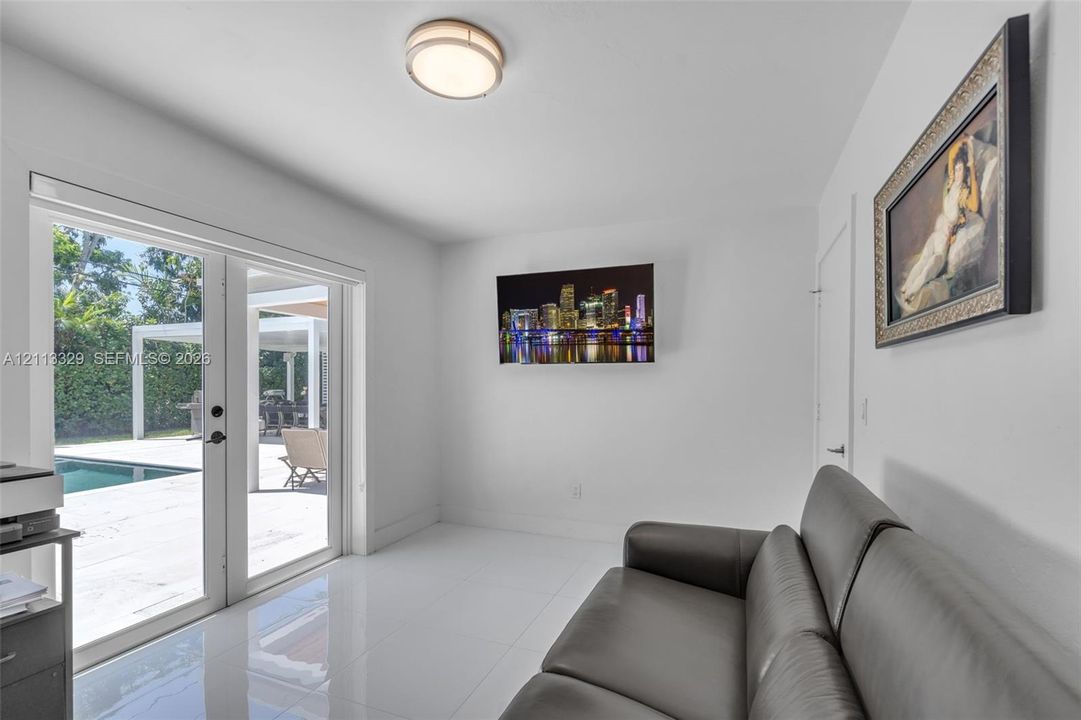 Interior space featuring polished tile flooring, flush-mount circular lighting, and glass-paned double doors opening to an exterior pool area