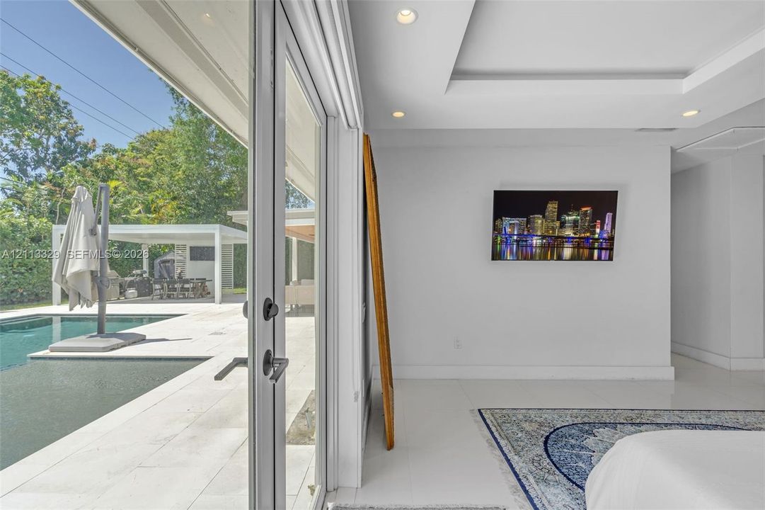 Floor-to-ceiling glass panel doors, tray ceiling with recessed lighting, and polished stone-finish flooring
