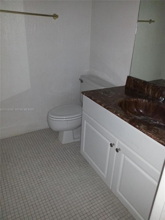 Vanity featuring a stone-look countertop with an integrated basin, white shaker-style cabinetry, a large wall-mounted mirror, and tile flooring