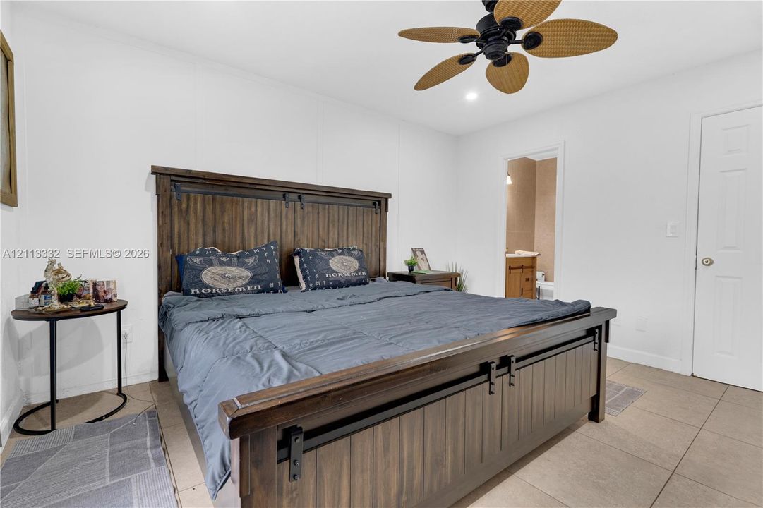 Neutral-toned room featuring large-format tile flooring, a multi-blade ceiling fan, and a six-panel interior door