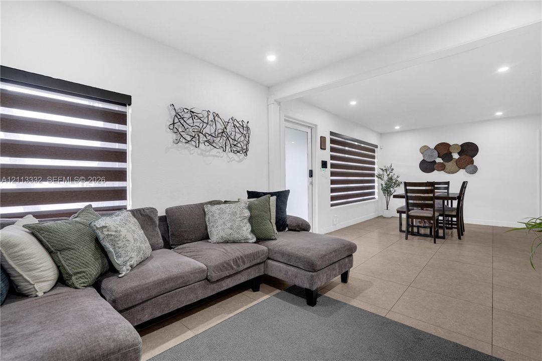 Open concept interior featuring large-format tile flooring, recessed lighting, and windows equipped with dual-layered roller shades