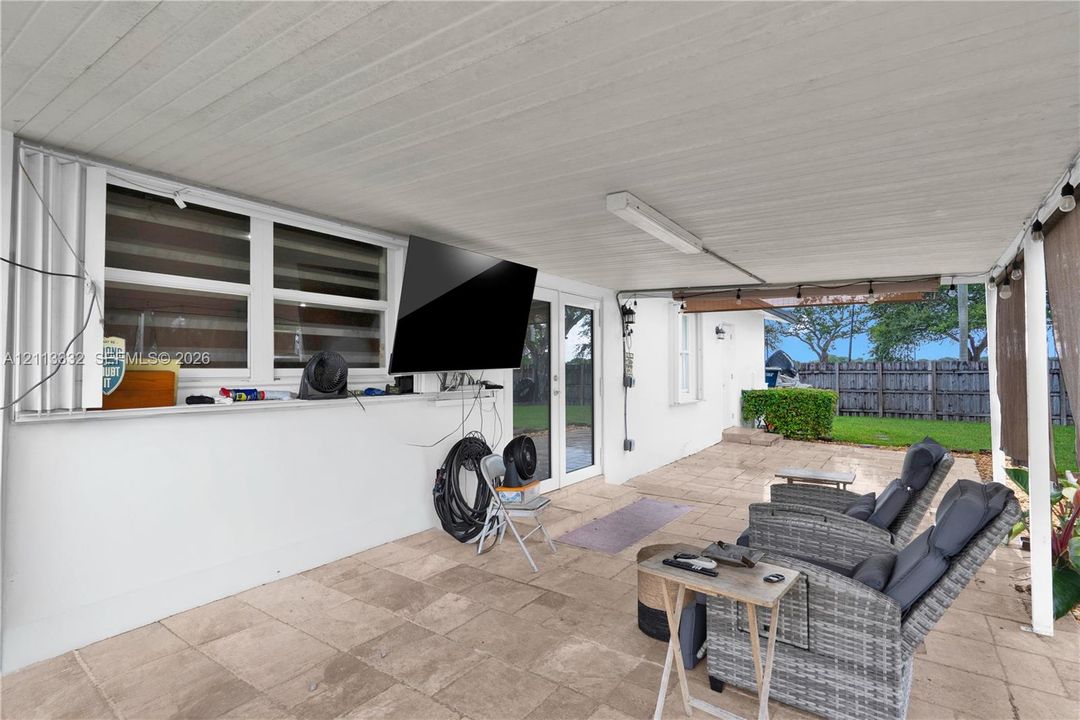 Covered outdoor patio featuring light-toned tile flooring, recessed ceiling lighting, and exterior access via glass-paneled doors