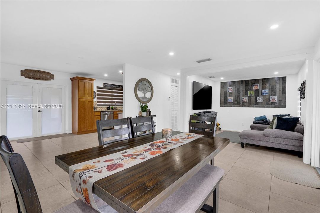 Open-concept interior featuring large-format tile flooring, recessed lighting, double-door entryway, and vertical plank accent wall